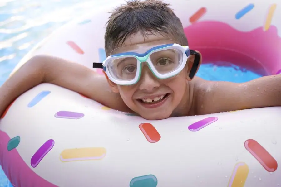 Dreng svømmer i pool med badering