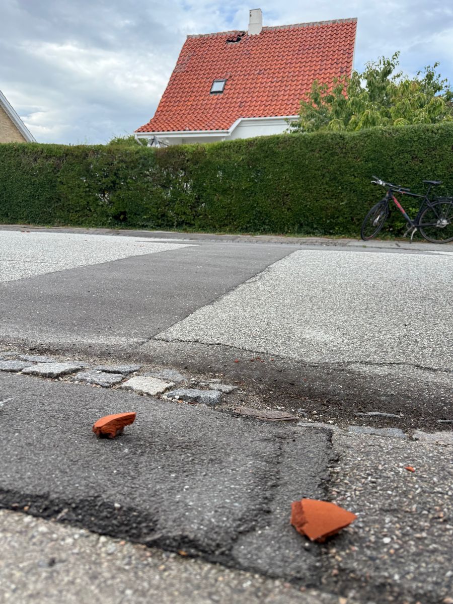 Teglsten på gaden efter lynnedslag i hus